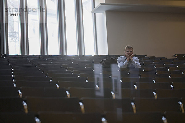 Gelangweilter Student  der allein im Hörsaal sitzt und der Vorlesung zuhört