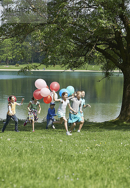 Kinder laufen im Park mit Luftballons  München  Bayern  Deutschland