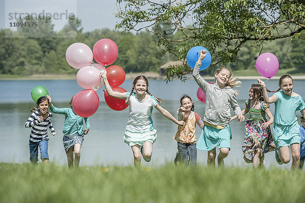 Kinder laufen im Park mit Luftballons  München  Bayern  Deutschland