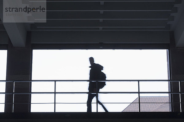 Silhouette eines jungen Schülers  der in einem Korridor geht