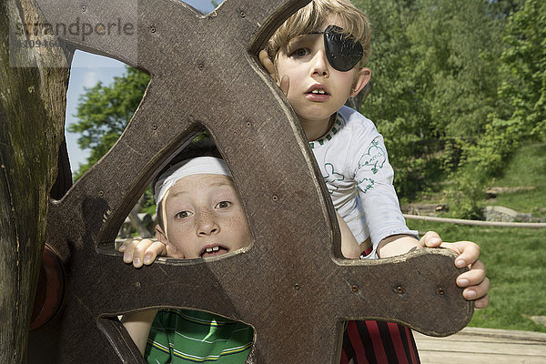 Zwei Jungen spähen aus dem Ruder eines Piratenschiffs auf einem Abenteuerspielplatz  Bayern  Deutschland