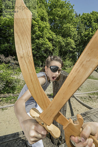 Zwei Mädchen  die sich als Piraten ausgeben und mit Schwertern auf einem Abenteuerspielplatz kämpfen  Bayern  Deutschland