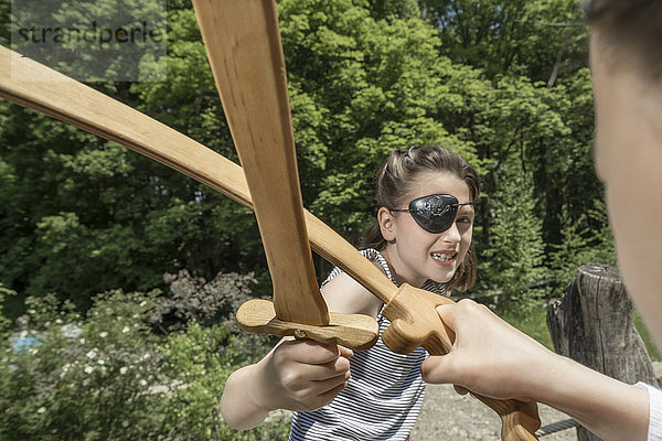 Zwei Mädchen  die sich als Piraten ausgeben und mit Schwertern auf einem Abenteuerspielplatz kämpfen  Bayern  Deutschland