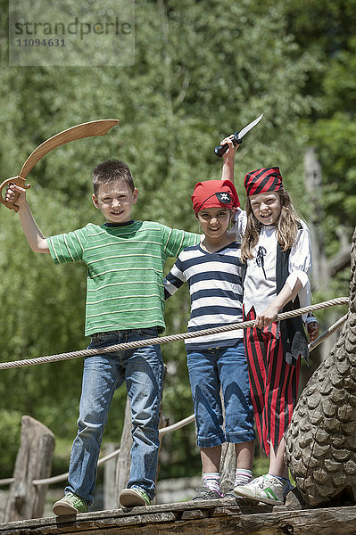 Drei als Piraten verkleidete Freunde spielen auf einem Piratenschiff auf einem Abenteuerspielplatz  Bayern  Deutschland