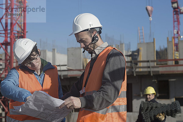 Zwei Ingenieure betrachten einen Bauplan auf einer Baustelle