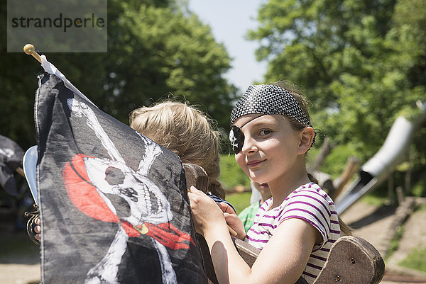 Porträt eines als Pirat verkleideten Mädchens mit Piratenflagge auf einem Abenteuerspielplatz  Bayern  Deutschland