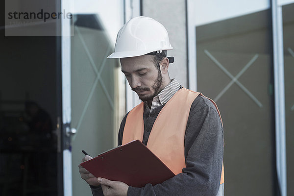 Junger männlicher Ingenieur bei der Arbeit auf einer Baustelle