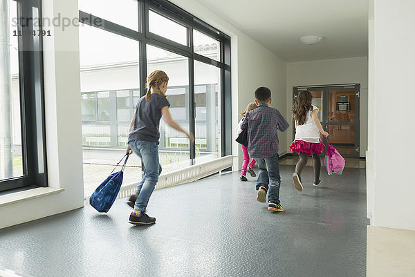 Kinder laufen mit Sporttaschen im Flur einer Sporthalle  München  Bayern  Deutschland