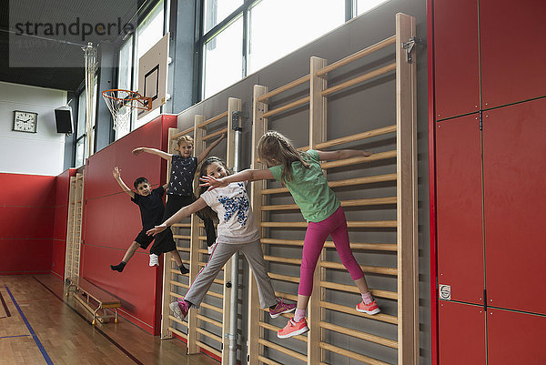 Vier Kinder trainieren an der Sprossenwand in einer Sporthalle  München  Bayern  Deutschland