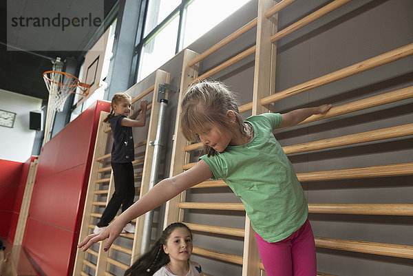 Drei Mädchen trainieren an der Sprossenwand in einer großen Turnhalle  München  Bayern  Deutschland