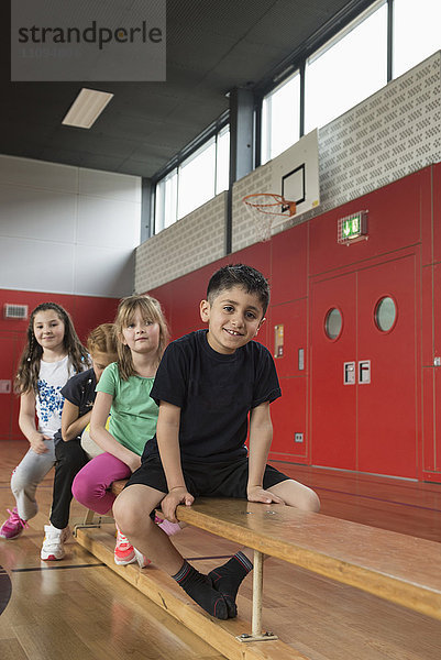 Kinder sitzen auf einer Bank in einer Sporthalle  Bayern  München  Deutschland