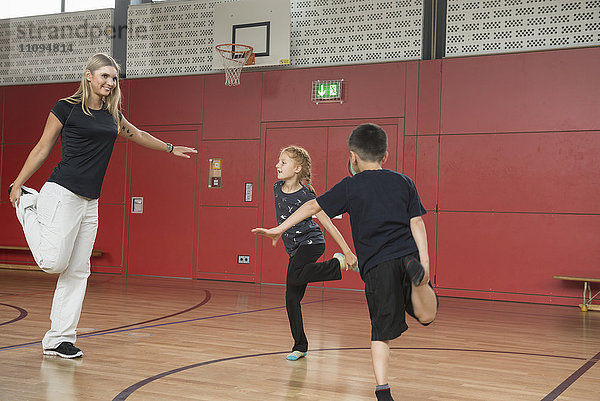 Lehrerin mit Kindern beim Sport in einer Sporthalle  München  Bayern  Deutschland