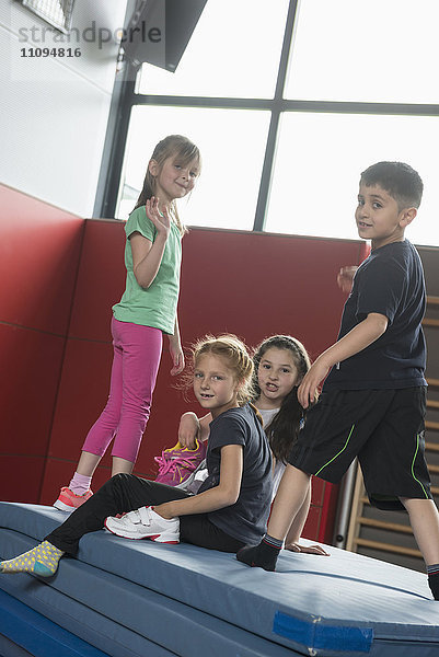 Kinder spielen auf einem Stapel von Sportmatten in einer Sporthalle  München  Bayern  Deutschland