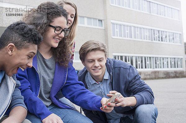 Universitätsstudenten  die sich mit ihrem Handy auf dem Campus vergnügen  Bayern  Deutschland