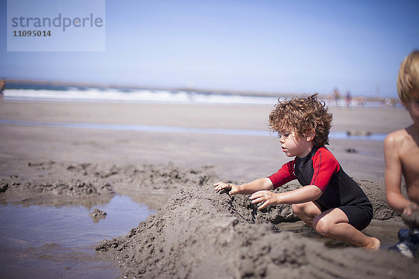 Zwei kleine Jungen bauen eine Sandburg im Sand am Strand  Viana do Castelo  Region Norte  Portugal