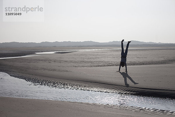 Mittlere erwachsene Frau im Handstand am Strand  Renesse  Schouwen-Duiveland  Zeeland  Niederlande