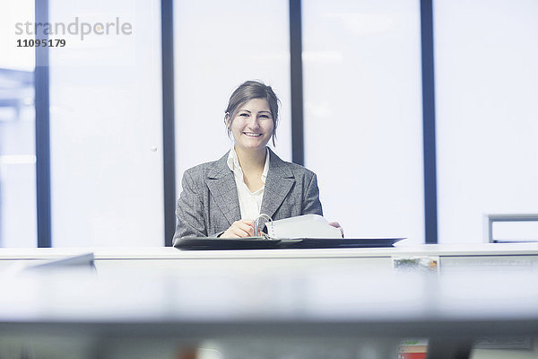 Geschäftsfrau beim Lesen von Dokumenten und Lächeln im Büro  Freiburg im Breisgau  Baden-Württemberg  Deutschland