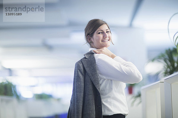 Geschäftsfrau mit Anzug auf der Schulter und lächelnd im Büro  Freiburg im Breisgau  Baden-Württemberg  Deutschland