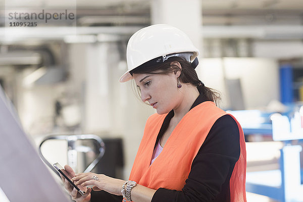 Ingenieurin bei der Nutzung eines Smartphones in einer Industrieanlage  Freiburg im Breisgau  Baden-Württemberg  Deutschland