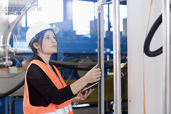 Ingenieurin  die ein digitales Tablet benutzt und die Maschine in einer Industrieanlage untersucht  Freiburg im Breisgau  Baden-Württemberg  Deutschland