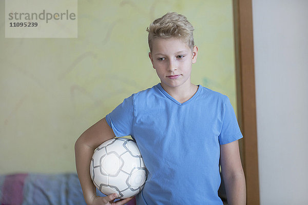 Junge mit Fußball unter dem Arm und Blick nach unten  Freiburg im Breisgau  Baden-Württemberg  Deutschland