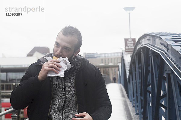 Mittelgroßer erwachsener Mann beim Verzehr von Fast Food  Freiburg im breisgau  Baden-württemberg  Deutschland