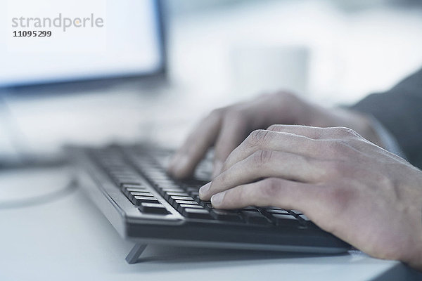 Ausgeschnittenes Bild eines Geschäftsmanns  der auf einer Computertastatur tippt  Freiburg im Breisgau  Baden-Württemberg  Deutschland