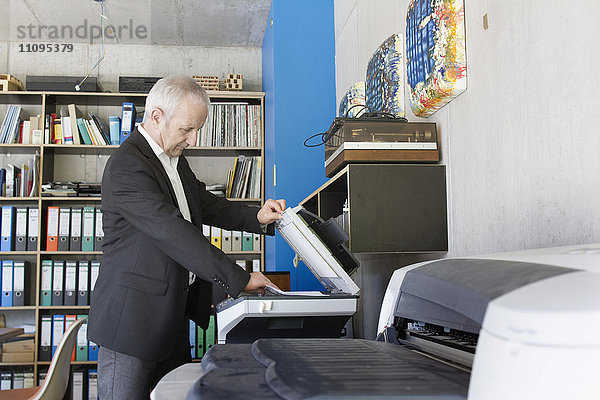 Älterer Geschäftsmann bei der Benutzung eines Fotokopiergeräts im Büro  Freiburg im Breisgau  Baden-Württemberg  Deutschland