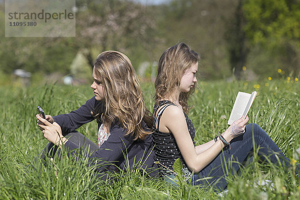 Teenager-Mädchen sitzen auf einem Feld  Freiburg im Breisgau  Baden-Württemberg  Deutschland