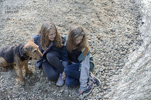 Teenager-Mädchen sitzen mit ihrem Hund am Flussufer  Freiburg im Breisgau  Baden-Württemberg  Deutschland
