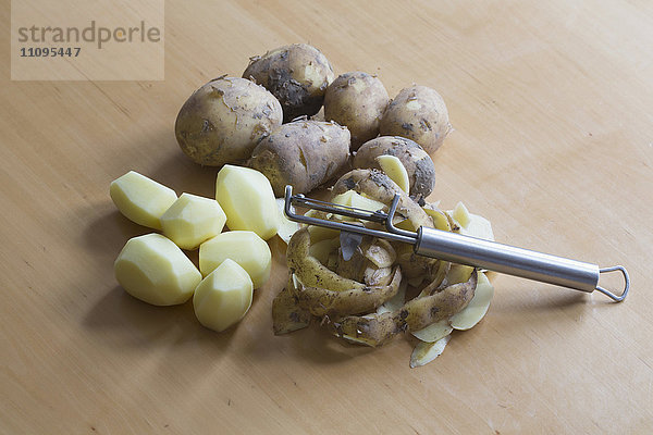 Nahaufnahme von geschälten und rohen Kartoffeln mit Schälmaschine auf einem Tisch  Freiburg im breisgau  Baden-württemberg  Deutschland