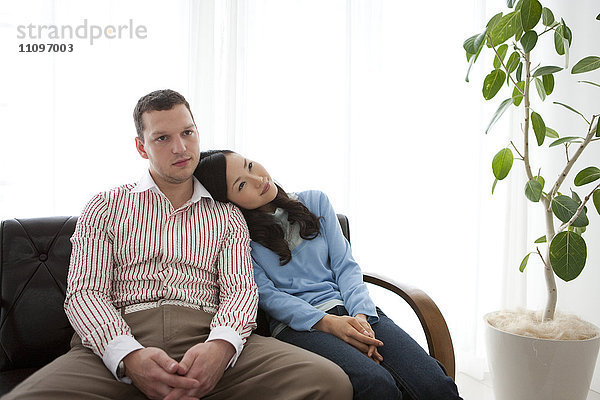 Junges Paar auf Sofa sitzend