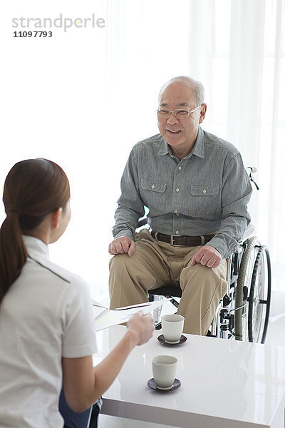 Krankenschwester im Gespräch mit einem älteren männlichen Patienten