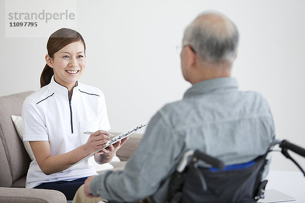 Krankenschwester im Gespräch mit einem älteren männlichen Patienten