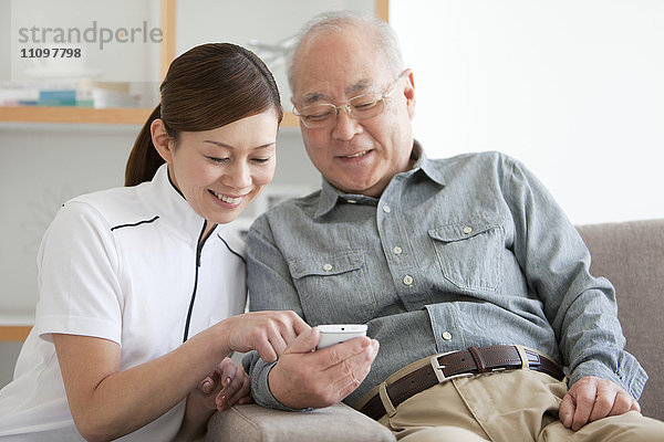 Älterer männlicher Patient und Krankenpfleger mit Blick auf das Mobiltelefon