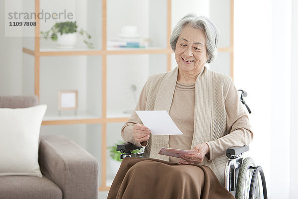 Ältere Frau im Rollstuhl liest Brief