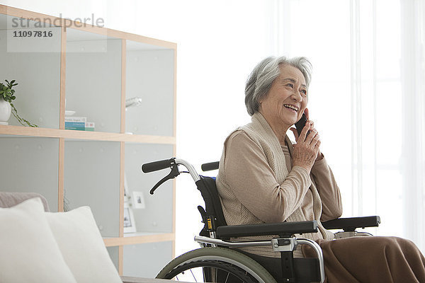 Ältere Frau im Rollstuhl benutzt Telefon