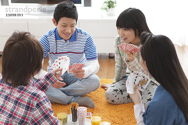 Teenager spielen Karten im Wohnzimmer