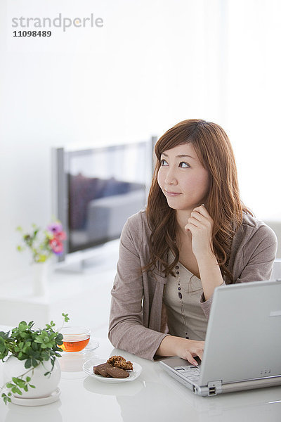 Junge Frau mit Laptop im Wohnzimmer