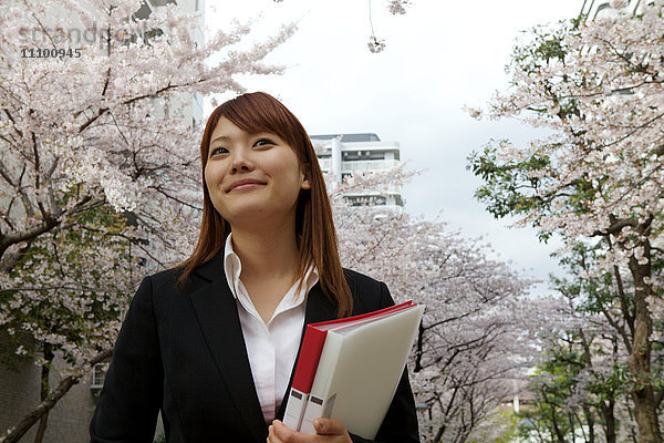 Geschäftsfrau inmitten von Kirschblütenbäumen