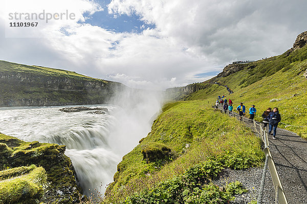 Touristen besuchen den Gullfoss (Goldener Wasserfall)  einen Wasserfall in der Schlucht des Flusses Hvita im Südwesten Islands  Polarregionen