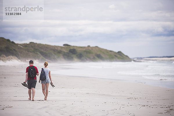 Touristen bei einem Spaziergang am Rarawa Beach  einem beliebten und schönen weißen Sandstrand in der Region Northland  Nordinsel  Neuseeland  Pazifik
