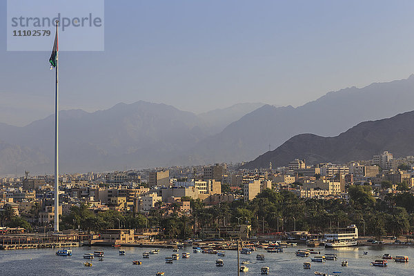 Blick von oben auf die Strandpromenade von Aqaba mit riesiger jordanischer Flagge  Booten und dunstigen Bergen in der Ferne  Aqaba  Jordanien  Naher Osten