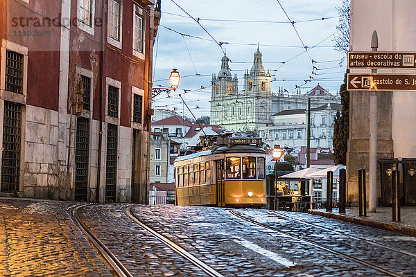 Romantische Atmosphäre in den alten Straßen von Alfama mit der Burg im Hintergrund und der Straßenbahnlinie 28  Lissabon  Portugal  Europa