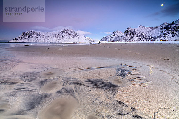 Der Vollmond spiegelt sich auf dem Sand in der surrealen Szenerie des Skagsanden-Strandes  Flakstad  Nordland  Lofoten  Arktis  Norwegen  Skandinavien  Europa