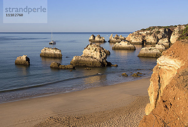 Blick auf den feinen Sandstrand  der in der Morgendämmerung vom blauen Meer umspült wird  Praia do Alemao  Portimao  Bezirk Faro  Algarve  Portugal  Europa