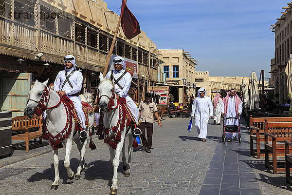 Belebte Straßenszene mit traditionell gekleideten berittenen Polizisten und Einkäufern  Souq Waqif  Doha  Katar  Naher Osten