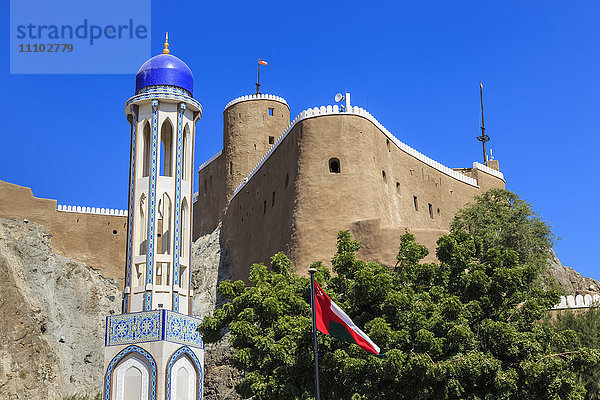 Minarett einer blauen Kuppelmoschee  Oman  Naher Osten Nationalflagge und Al-Mirani Fort  Old Muscat  Oman  Naher Osten