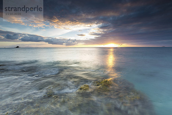 Die Lichter des Sonnenuntergangs spiegeln sich im blauen Meer  Hawksbill Bay  Antigua  Antigua und Barbuda  Leeward Islands  Westindische Inseln  Karibik  Mittelamerika