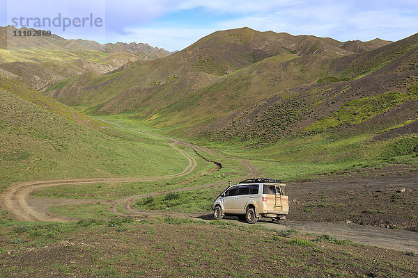 Fahrzeug fährt abseits der Straße durch üppige Berge  Gurvan Saikhan National Park  in der Nähe von Yolyn Am (Yol Tal)  Wüste Gobi  Mongolei  Zentralasien  Asien